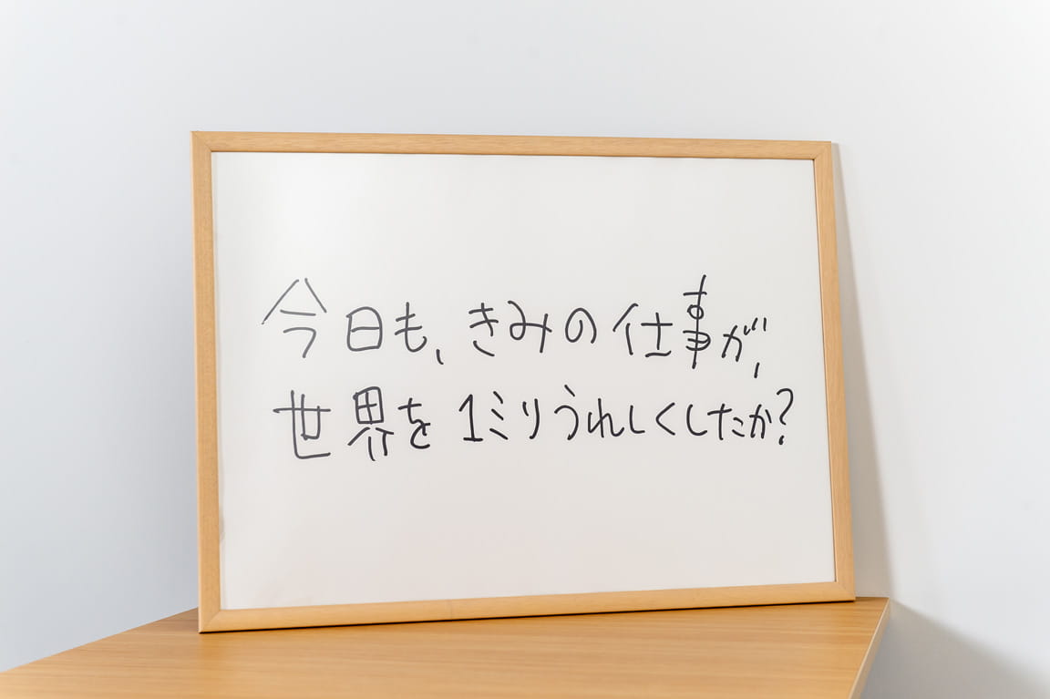 ホワイトボードの写真 「今日、きみの仕事が、世界を１ミリうれしくしたか？」